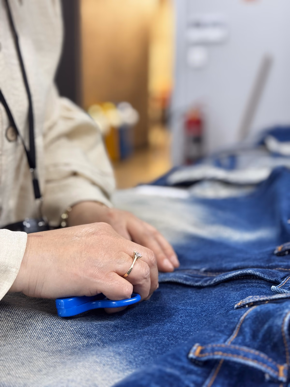 Finishing a pair of blue denim jeans by hand in the studio