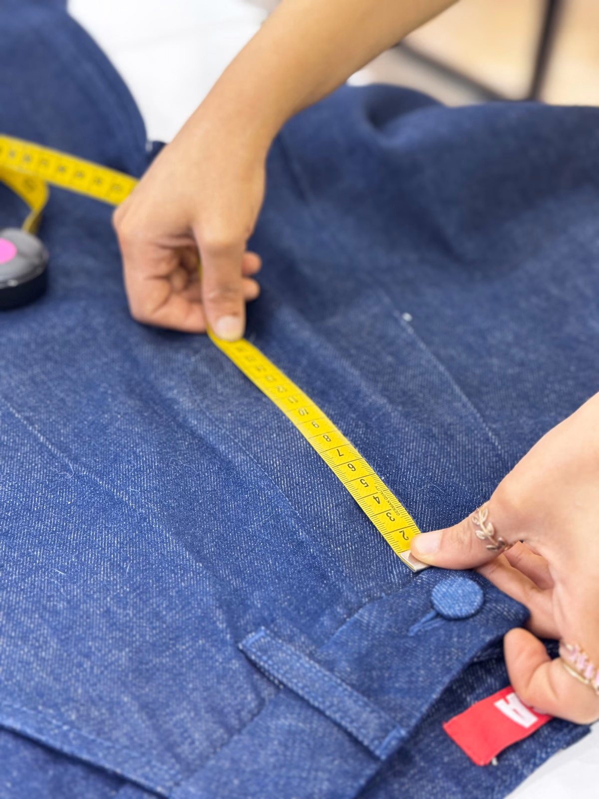 Measuring an indigo denim waistband with a tape in the studio