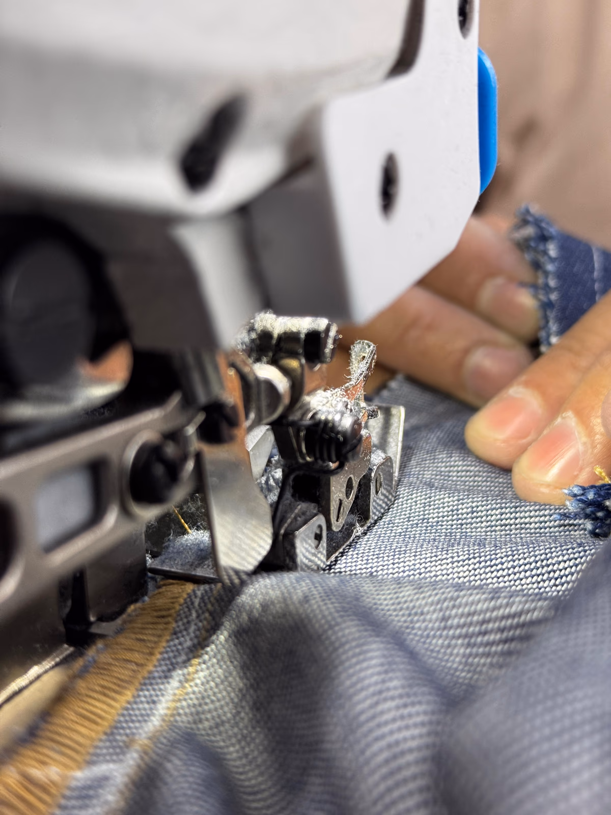 Close-up of an industrial sewing machine stitching blue denim