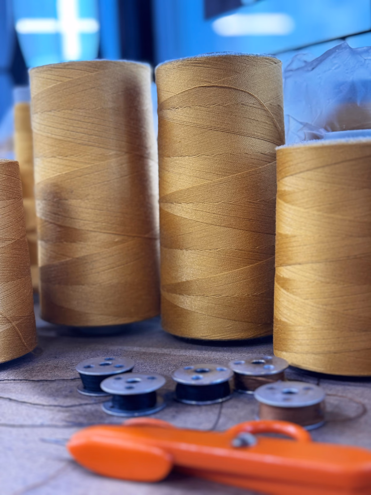 Gold thread spools, bobbins, and thread nippers on a studio table