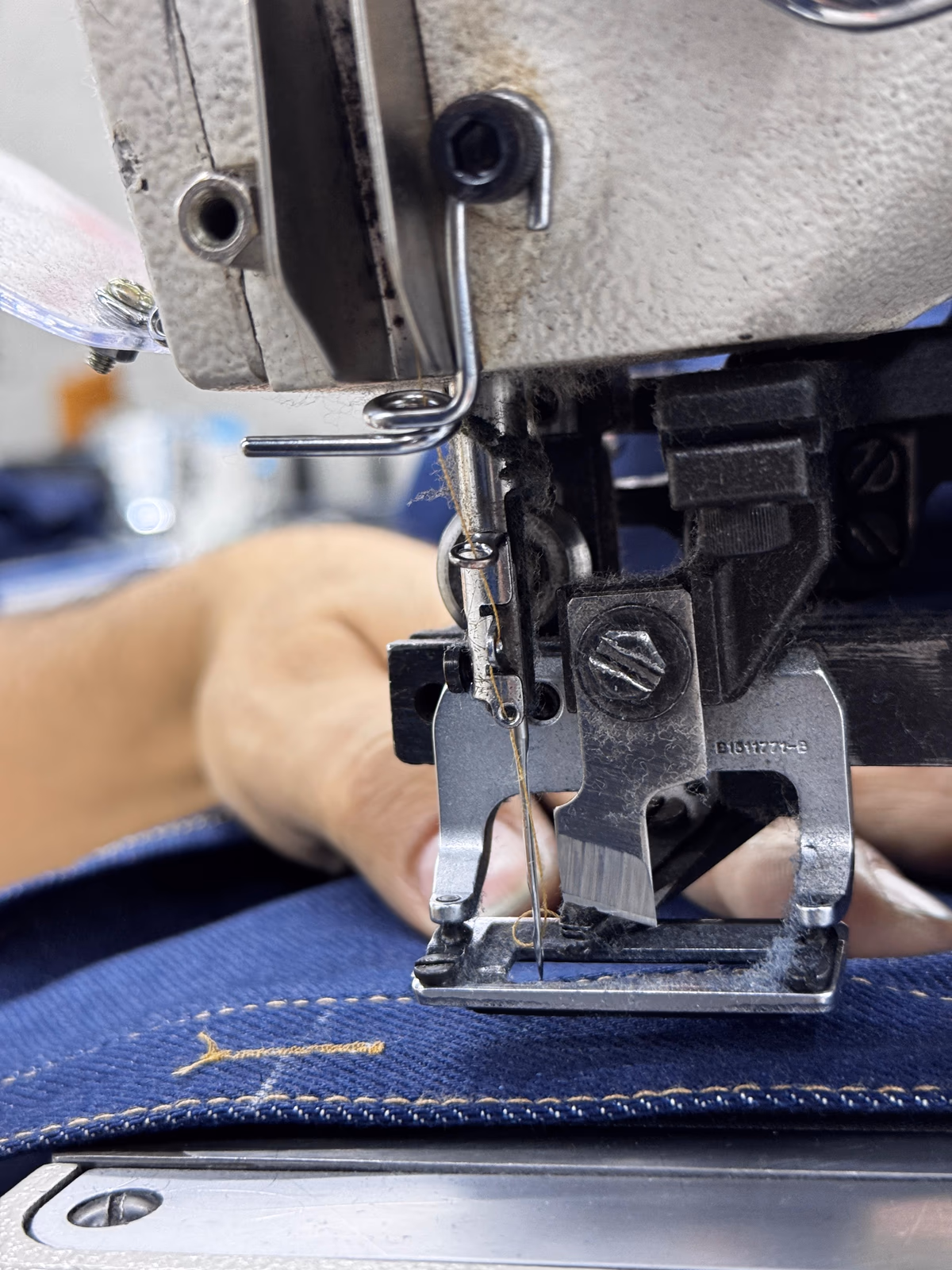 Industrial sewing machine needle stitching gold topstitch on denim