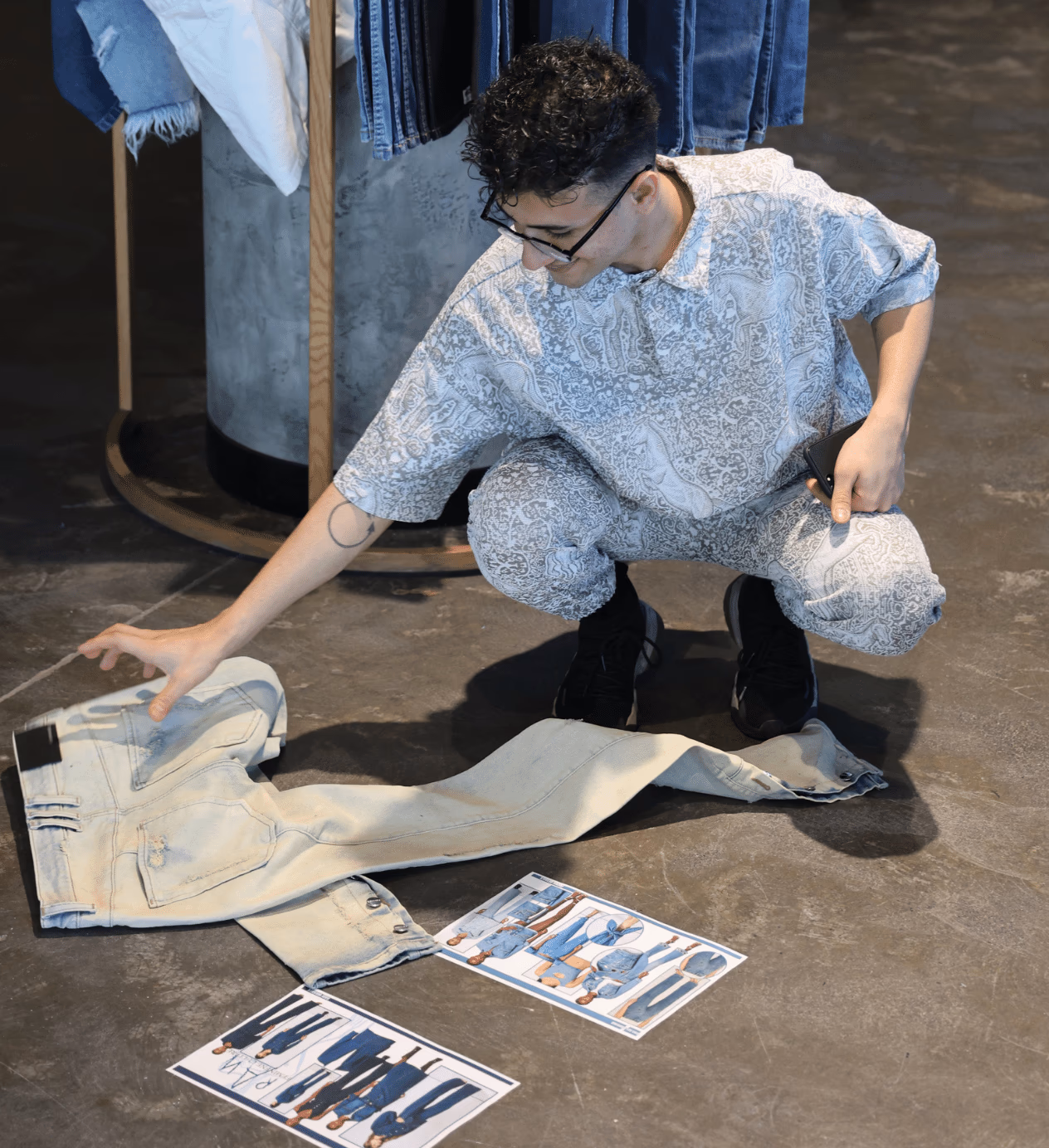 ALLDENIMS stylist reviewing light-wash jeans on the studio floor