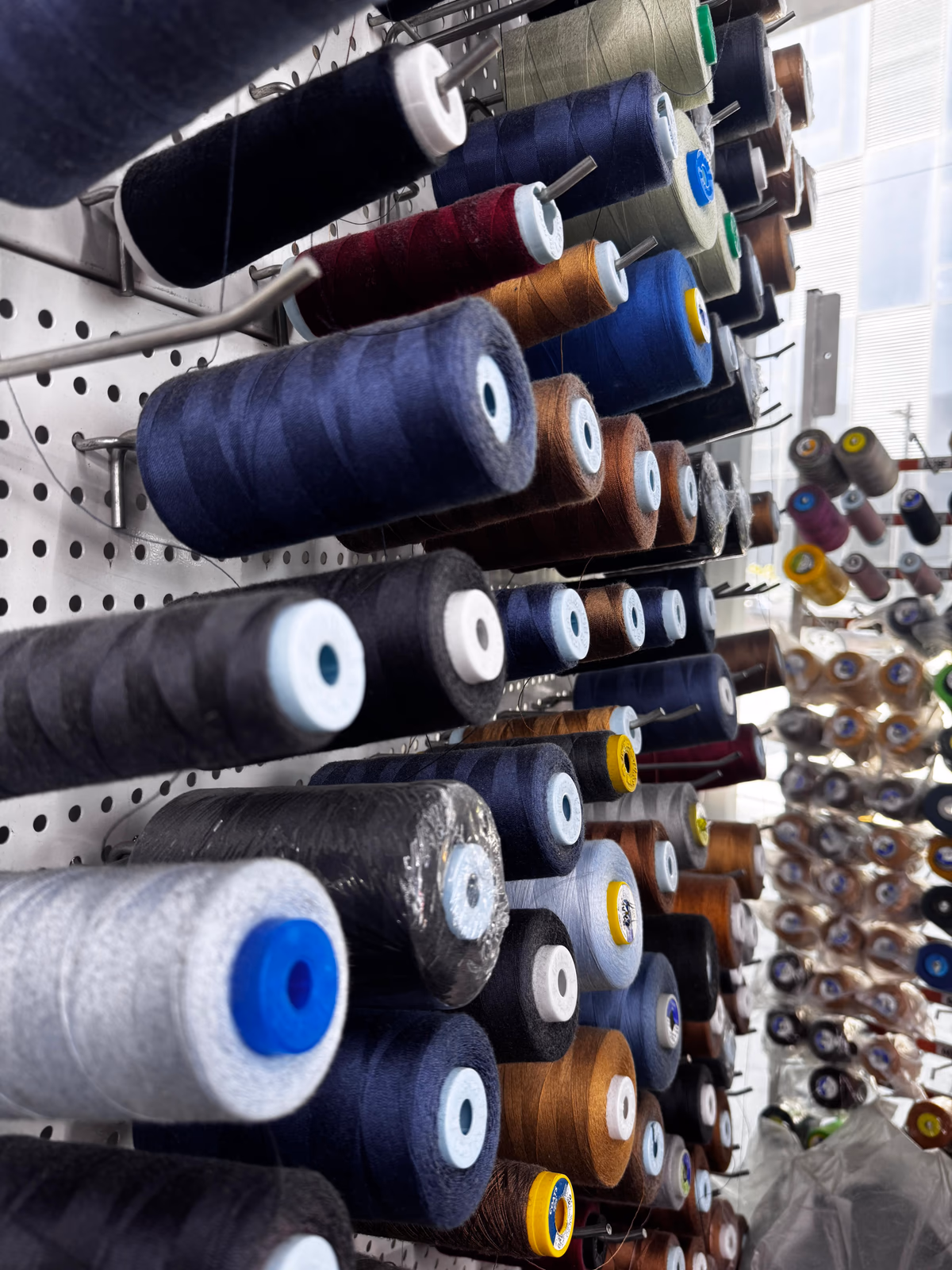 ALLDENIMS thread wall — industrial spools in the production studio